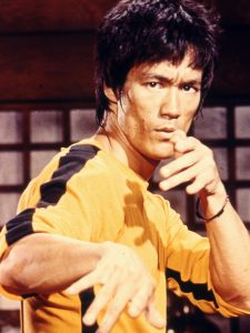 映画『死亡遊戯』で黄色のトラックスーツを着てジークンドーの構えをとっているブルース・リー